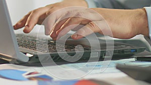 Businessman typing weekly report on laptop computer, close-up of male hands