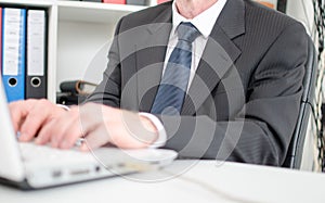 Businessman typing on a white laptop computer keyboard