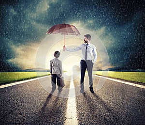 Businessman with umbrella that protect a child. Concept of young economy and startup protection photo