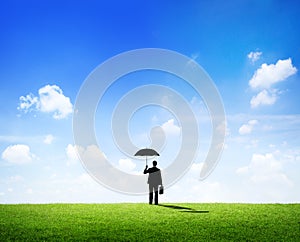 Businessman with Umbrella Standing on a Field