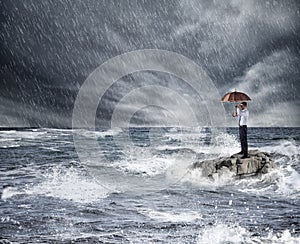 Businessman with umbrella during storm in the sea. Concept of insurance protection photo