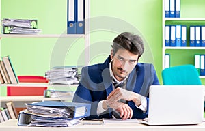 Businessman unhappy with excessive work sitting in the office