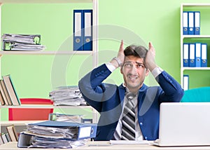 Businessman unhappy with excessive work sitting in the office