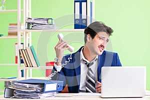 Businessman unhappy with excessive work sitting in the office