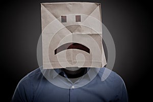 Businessman with an unhappy face on a paper bag