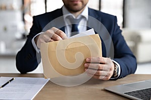 Businessman unpacking document at workplace, opening envelope