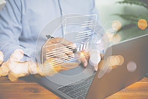 Businessman uses a pen to sign an electronic signature approved on an electronic document with a laptop on a wooden table.