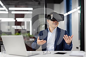 Businessman uses virtual reality glasses VR simulator, inside office at workplace, man in business suit, boss at online