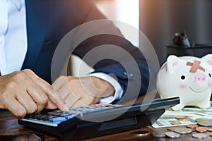 Businessman using calculator calculate of finances and piggy bank with money on table in office. business financing accounting