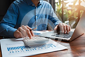 Businessman using calculator, laptop for accounting and budgeting