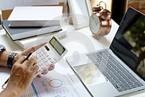 Businessman using calculator and laptop computer for calculating with finance paper, tax, accounting. Finance concept