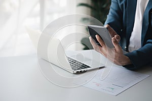 Businessman using a calculator to calculate numbers on a company's financial document