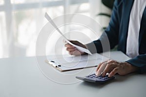 Businessman using a calculator to calculate numbers on a company's financial document