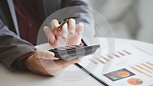 Businessman using a calculator to calculate numbers on a company's financial documents.