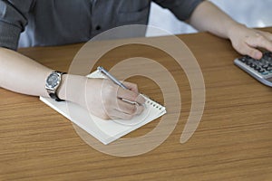 businessman using calculator and writing note on notepad