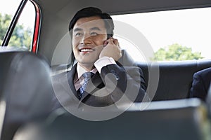 Businessman Using Cellphone In Backseat Of Car