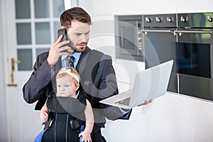 Businessman using cellphone and laptop while carrying daughter