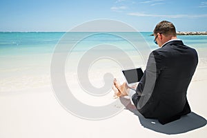 Businessman using computer on the beach