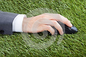 Businessman using computer mouse on grass