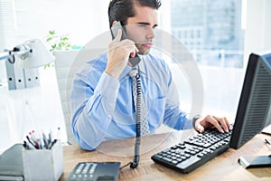 Businessman using computer and phoning