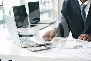 Businessman using computer to analyse the investment.