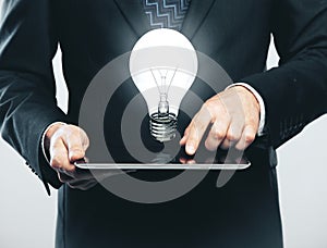 Businessman using digital tablet with lightbulb