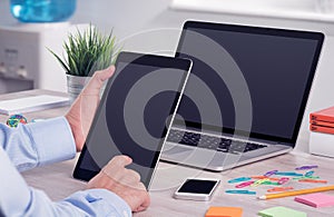 Businessman using ipad digital tablet pc and macbook laptop on the office desk photo