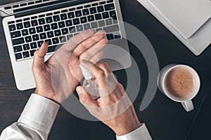 Businessman using disinfectant spray to disinfect hands while working office desk