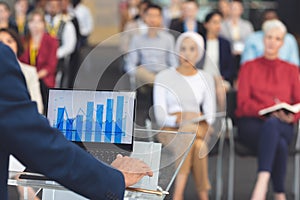 Businessman using graphs while he speaks at a business seminar