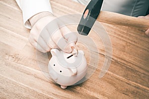 Businessman Using A Hammer To Force A Euro Coin Into A Pink Piggy Bank On A Wooden Table - Save Money Concept