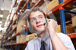 Businessman Using Headset In Distribution Warehouse