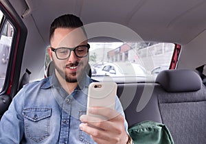 Businessman using his smart phone while on his commute to work in private vehicle transportation. Concept of journey, motivation,