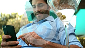 Businessman using his smartphone on deckchair