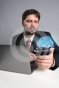 Businessman using his smartphone with a virtual cloud above it