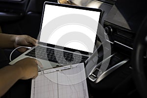 Businessman using laptop computer in car on the road with blank white screen