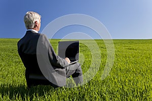 Businessman Using Laptop Computer in Green Fie