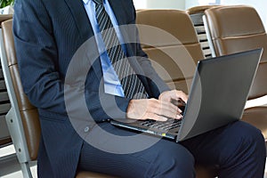 Businessman using laptop computer while sitting on the chair at the airport