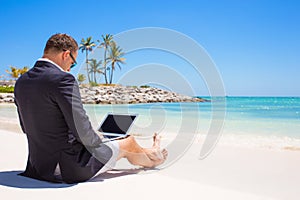 Businessman using laptop computer on tropical beach