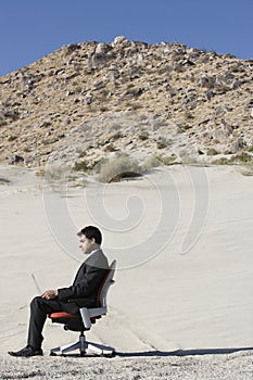 Businessman Using Laptop In Desert