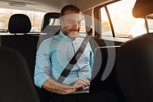 Businessman using laptop while going by car