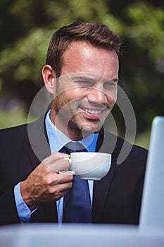 Businessman using laptop having a coffee