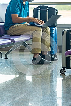 Businessman using laptop while sitting at waiting chair in airport