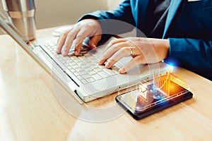 Businessman using laptop and smartphone screen display and technology advances in communications for business. The hologram