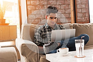 Businessman using laptop on sofa in coffee shop