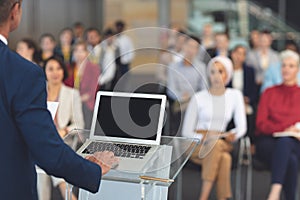 Businessman using laptop while speaking at a business seminar