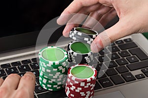 Businessman using laptop with stacked poker chips