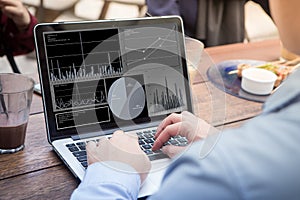 Businessman using laptop with stock chart statistics data