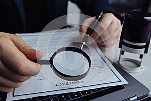 Businessman using magnifying glass to aprove a contract