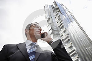 Businessman Using Mobile Phone Against Tall Building