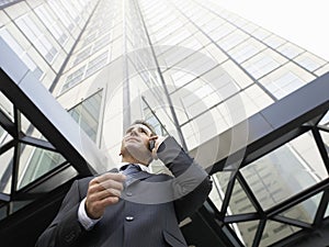 Businessman Using Mobile Phone Against Tall Office Building